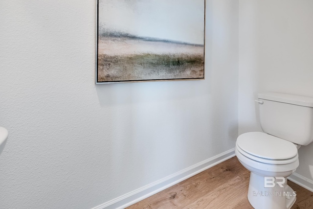 bathroom with baseboards, wood finished floors, and toilet