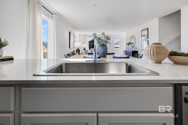 kitchen with a sink, gray cabinets, open floor plan, and light countertops