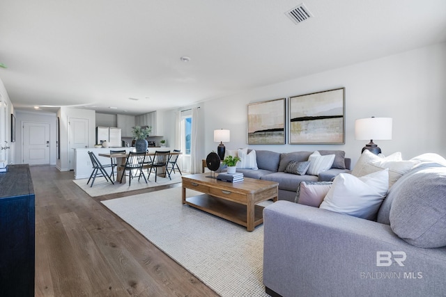 living area with visible vents and wood finished floors