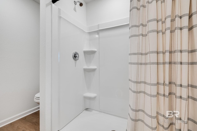 bathroom with wood finished floors, baseboards, curtained shower, and toilet