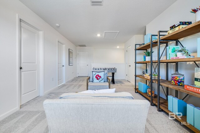living area featuring attic access, baseboards, light colored carpet, and visible vents