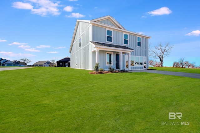 view of front of house featuring board and batten siding, driveway, and a front yard