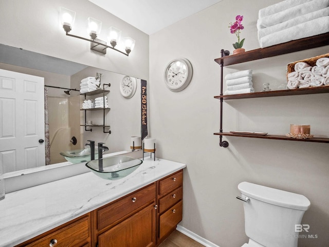 bathroom featuring walk in shower, vanity, and toilet