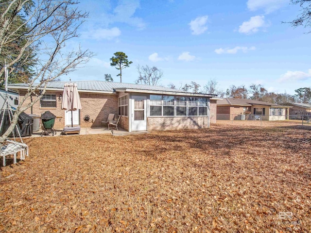 back of house with a patio area, a sunroom, and a lawn