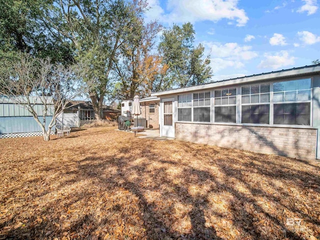 back of property featuring a sunroom and a lawn