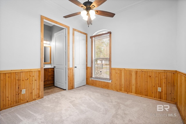 unfurnished bedroom with ceiling fan, light colored carpet, and ensuite bath