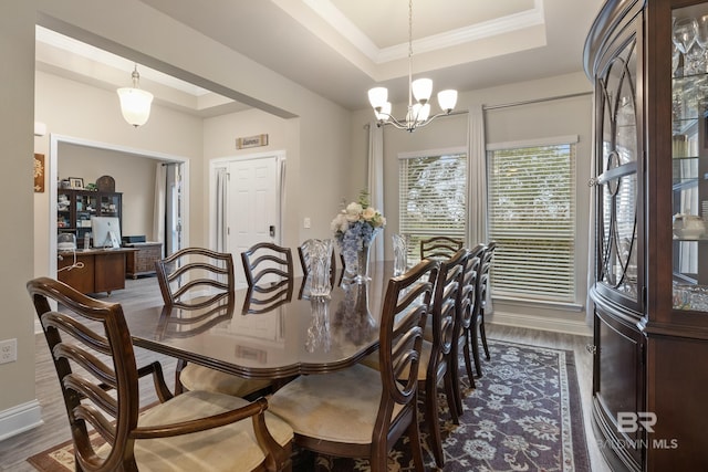 dining area featuring ornamental molding, a raised ceiling, dark wood-type flooring, and a notable chandelier