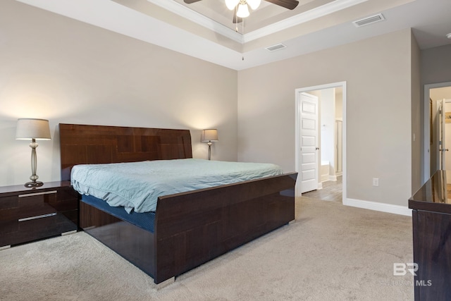 carpeted bedroom with a tray ceiling, connected bathroom, ceiling fan, and crown molding