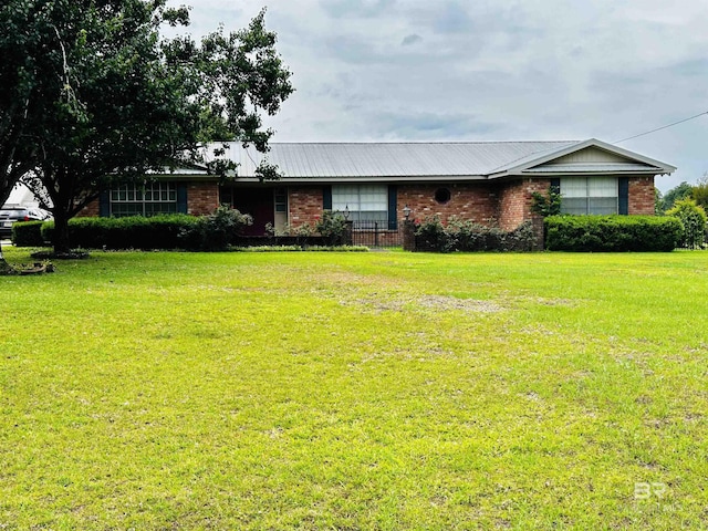 ranch-style home featuring brick siding, a front yard, and metal roof