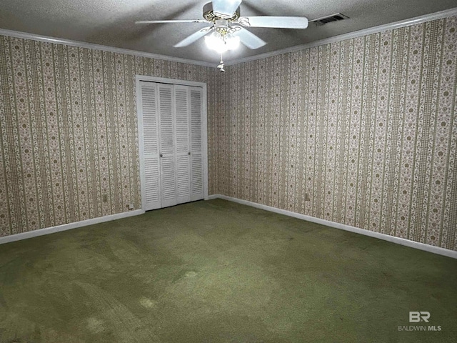 unfurnished bedroom with ornamental molding, a textured ceiling, a closet, carpet floors, and a ceiling fan
