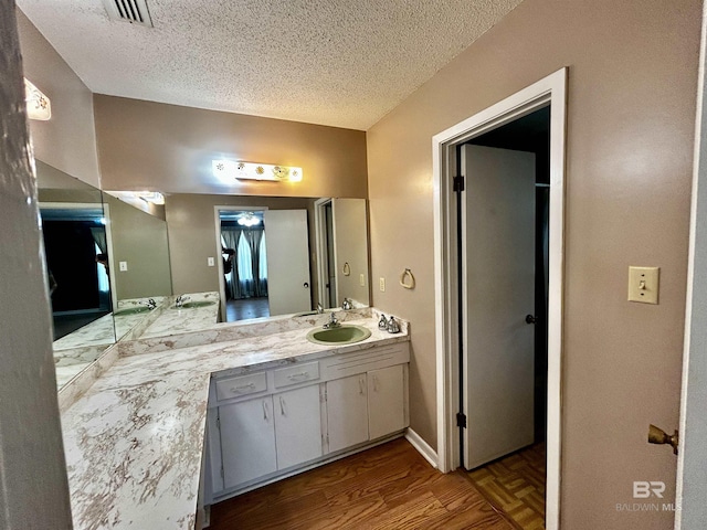 bathroom with a textured ceiling, wood finished floors, and vanity
