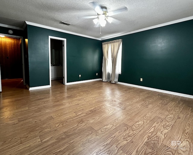 empty room featuring ceiling fan, wood finished floors, a textured ceiling, crown molding, and baseboards