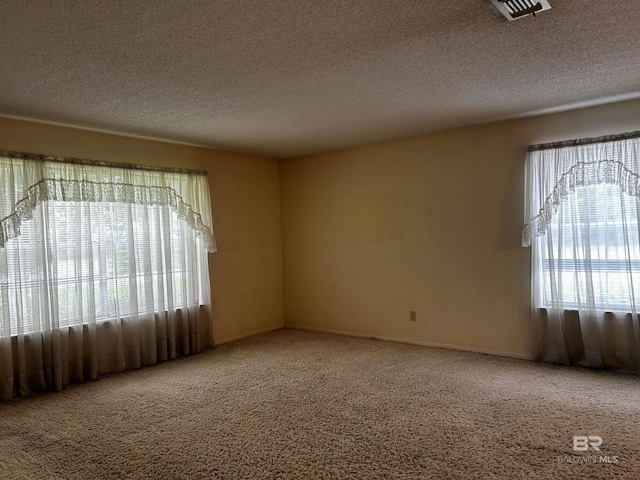 carpeted spare room with a textured ceiling and baseboards
