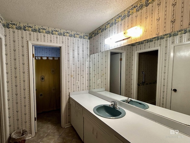 bathroom with wallpapered walls, tile patterned flooring, a textured ceiling, and vanity