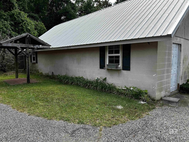 view of side of property featuring concrete block siding, a yard, and metal roof