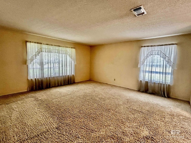 carpeted empty room with a textured ceiling