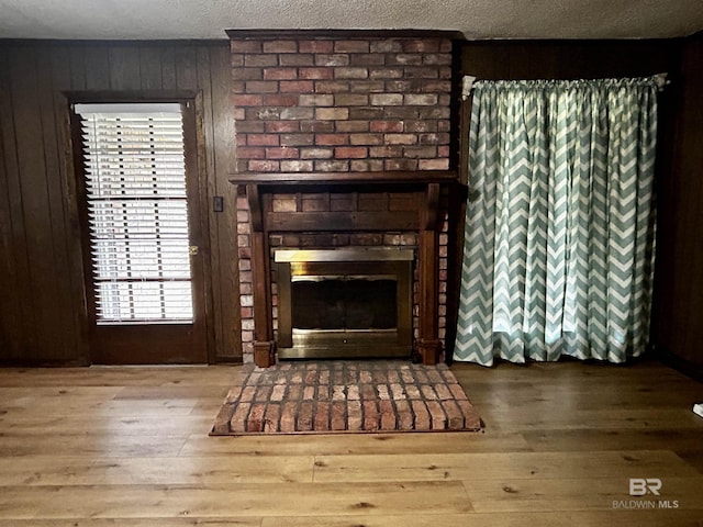 unfurnished living room with a brick fireplace, hardwood / wood-style flooring, healthy amount of natural light, and wooden walls