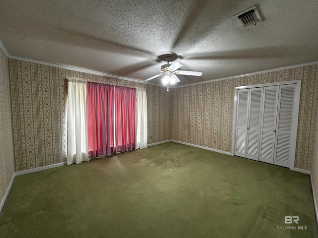 unfurnished bedroom featuring ornamental molding, carpet, wallpapered walls, a textured ceiling, and ceiling fan