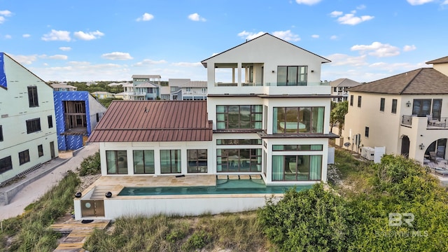 7276 Kiva Way, Gulf Shores, AL 36542 - rear view of property featuring a balcony, an outdoor pool, a standing seam roof, stucco siding, and metal roof