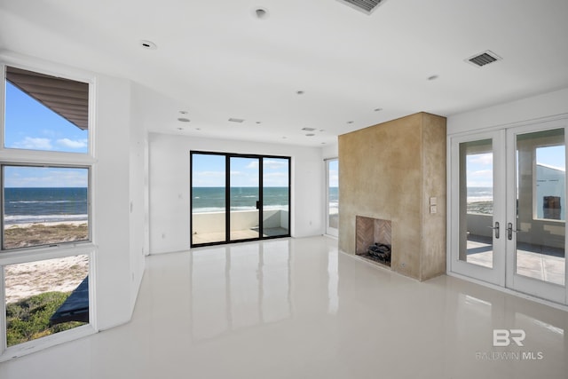 7276 Kiva Way, Gulf Shores, AL 36542 - unfurnished living room featuring french doors, view of water and beach, a fireplace, and recessed lighting