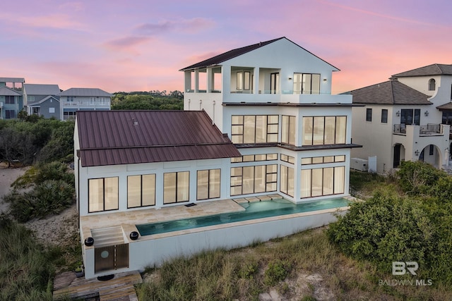 7276 Kiva Way, Gulf Shores, AL 36542 - back of property at dusk with a balcony, stucco siding, and metal roof