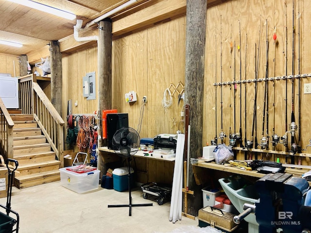 basement with a workshop area, wood walls, and electric panel