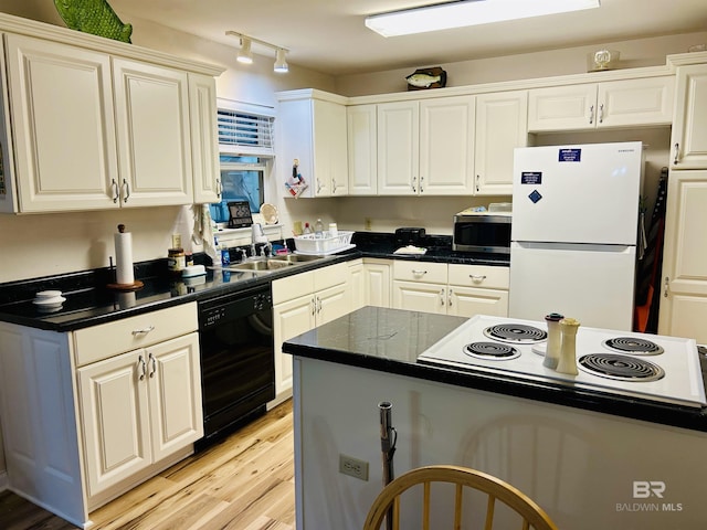 kitchen featuring freestanding refrigerator, stainless steel microwave, dishwasher, a sink, and dark countertops