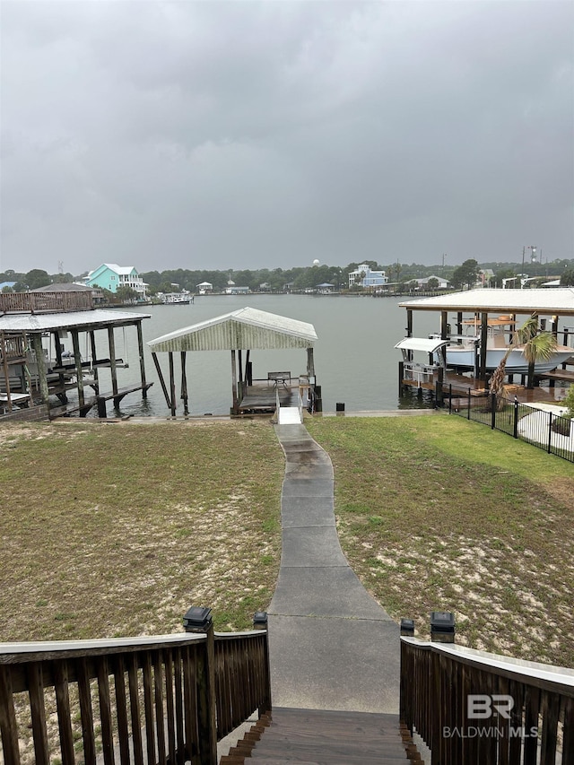 dock with boat lift, a water view, and a lawn