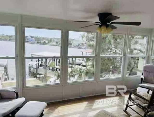 sunroom with plenty of natural light, a water view, and wood finished floors