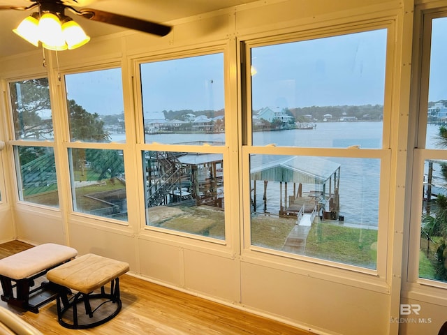 sunroom / solarium featuring a water view and wood finished floors