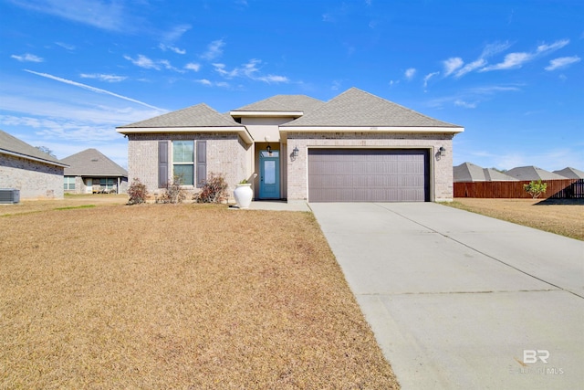 view of front of house featuring central AC unit, a front lawn, and a garage