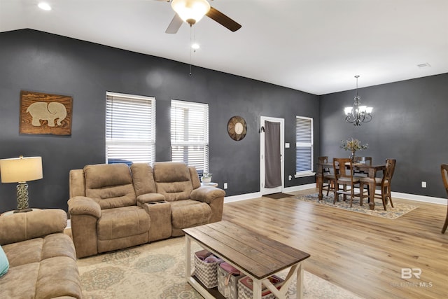 living room with ceiling fan with notable chandelier and light hardwood / wood-style floors