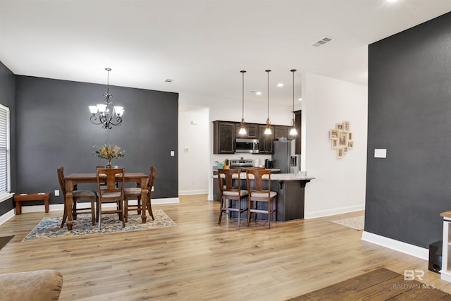 dining room featuring light wood-type flooring and a notable chandelier