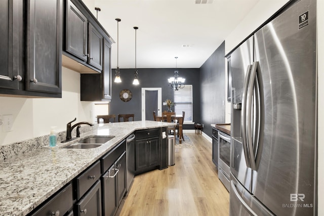 kitchen featuring a chandelier, stainless steel appliances, pendant lighting, sink, and light hardwood / wood-style flooring