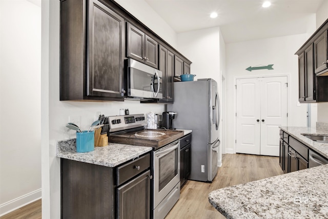 kitchen with stainless steel appliances, light hardwood / wood-style floors, dark brown cabinets, and light stone countertops