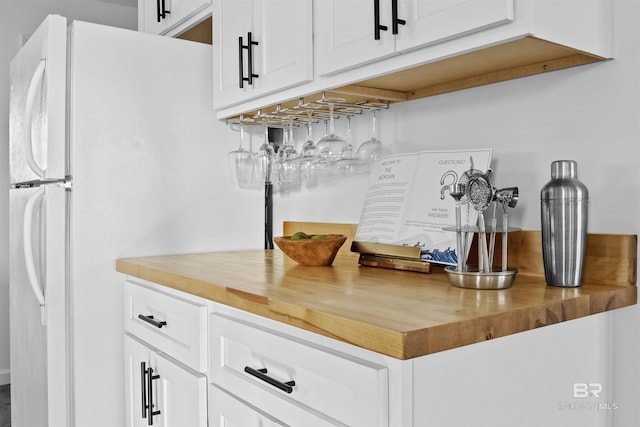 bar with butcher block counters, white cabinetry, and white fridge