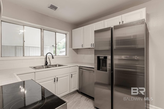 kitchen with backsplash, sink, white cabinets, and appliances with stainless steel finishes