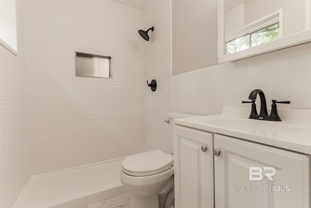 bathroom with vanity, toilet, tile walls, and a tile shower