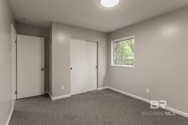 unfurnished bedroom featuring dark carpet and a closet