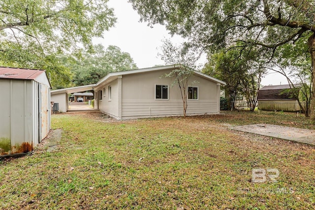 view of side of property featuring a carport, a storage unit, and a lawn