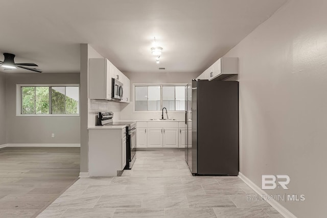 kitchen featuring white cabinetry, sink, ceiling fan, stainless steel appliances, and decorative backsplash