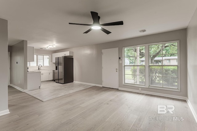 unfurnished living room featuring ceiling fan, light wood-type flooring, and sink