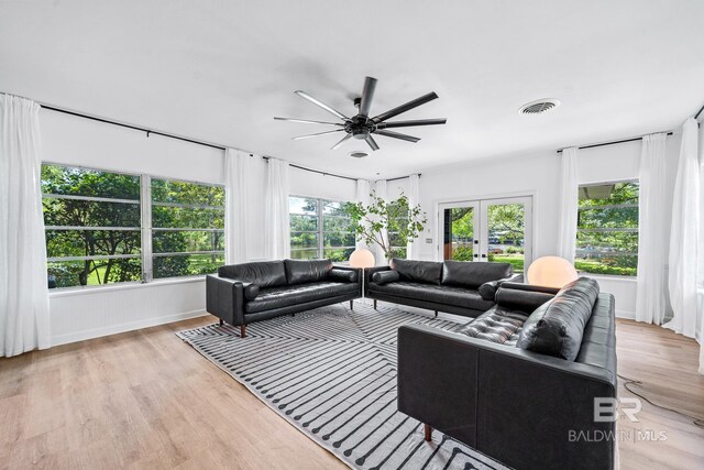 living room featuring french doors, light wood-type flooring, and ceiling fan