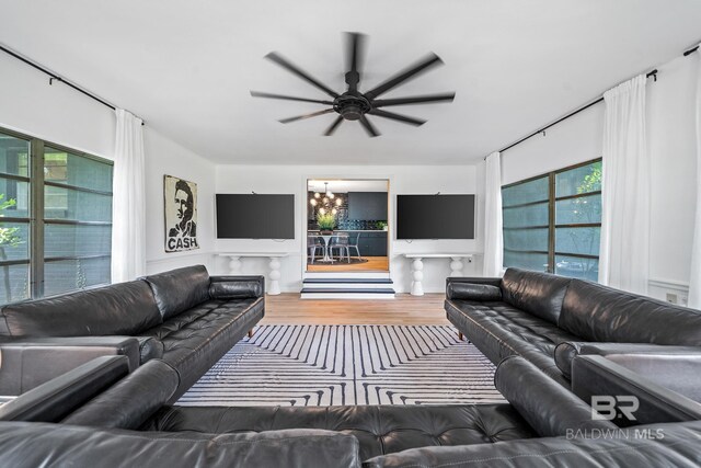 living room featuring ceiling fan with notable chandelier, wood-type flooring, and a wealth of natural light