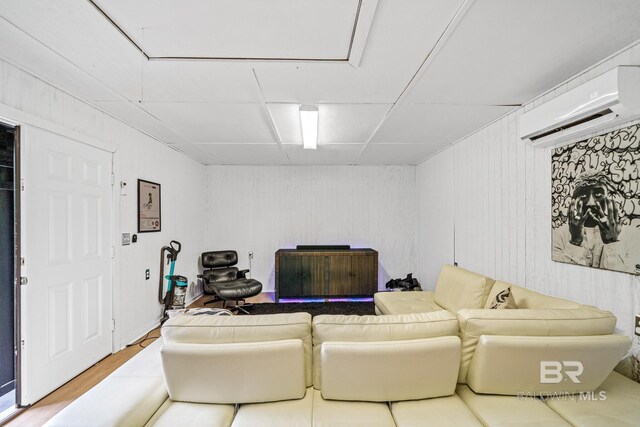 living room with hardwood / wood-style flooring, a wall unit AC, and a paneled ceiling