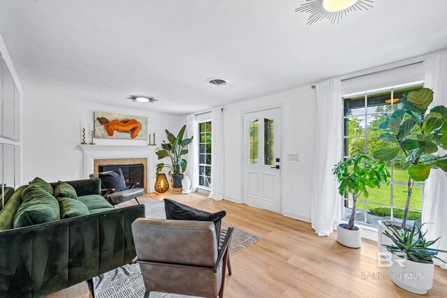 living room featuring a tile fireplace and light hardwood / wood-style floors