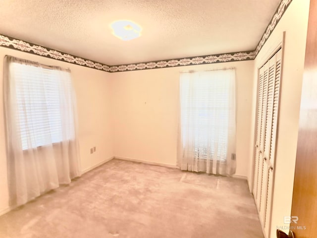 unfurnished bedroom with multiple windows, carpet, and a textured ceiling