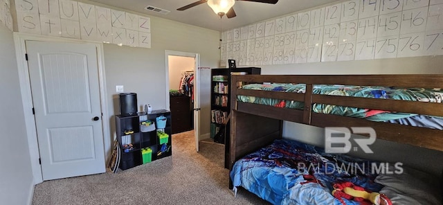 bedroom featuring a spacious closet, carpet floors, ceiling fan, and a closet