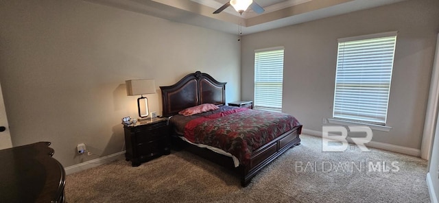 carpeted bedroom featuring ceiling fan and a raised ceiling