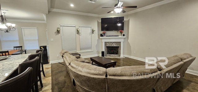 living room featuring dark hardwood / wood-style flooring, a fireplace, ceiling fan with notable chandelier, and ornamental molding